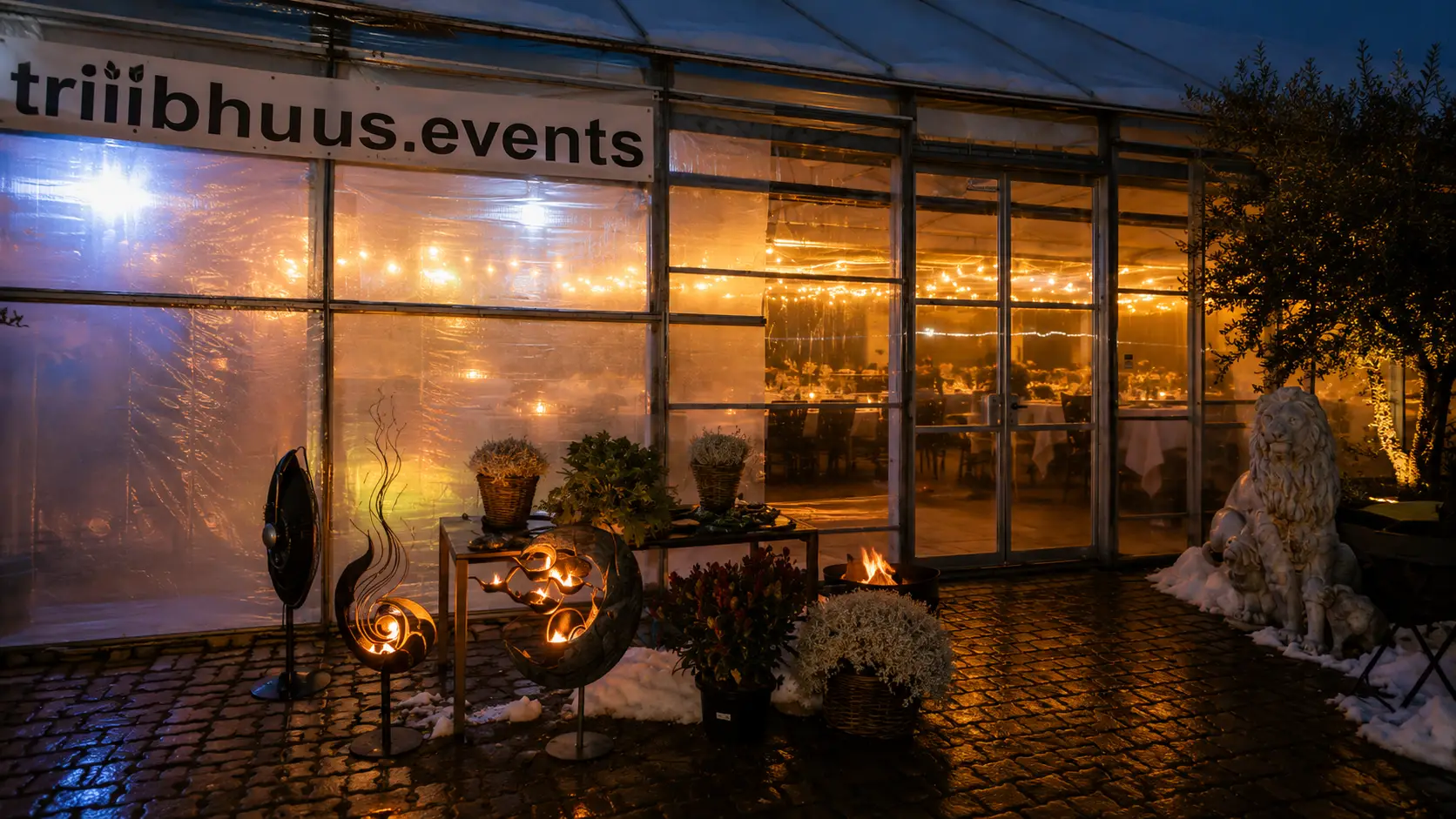 Das beleuchtete Triibhuus am Abend mit Feuerschalen vor dem Eingang – Triibhuus Events Rothrist